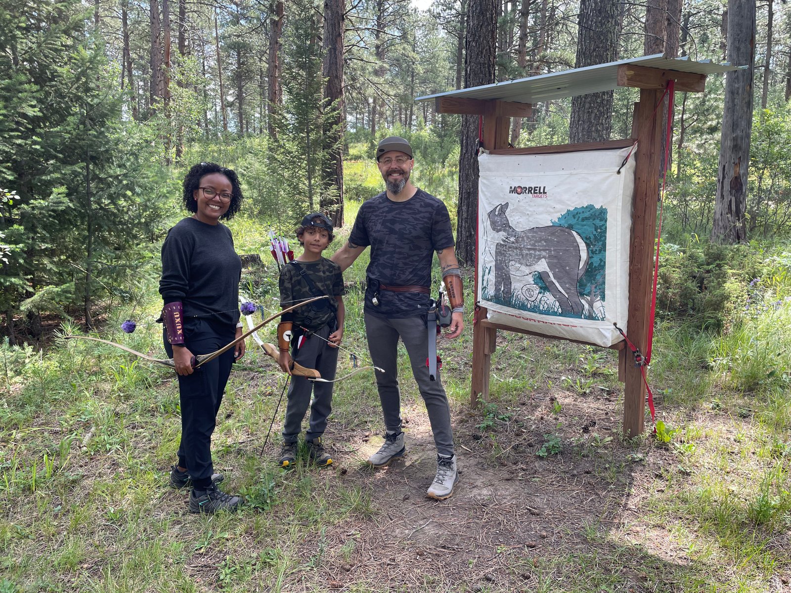 Family of archers posing beside a deer target in summer