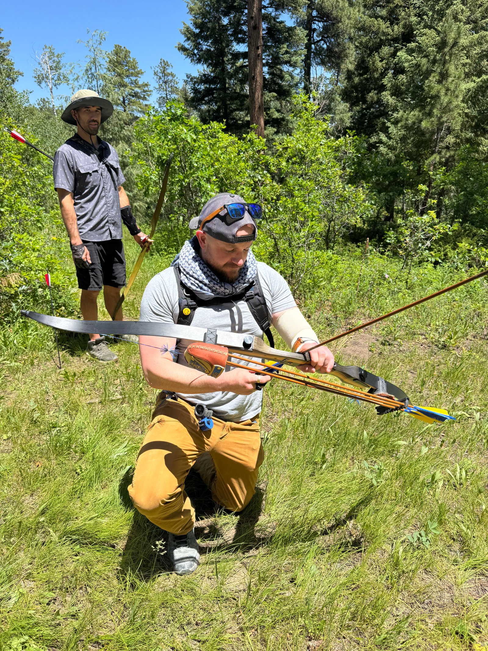 Archer kneeling to nock an arrow on the trail